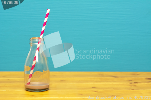 Image of Glass bottle with dregs of chocolate milkshake and a straw