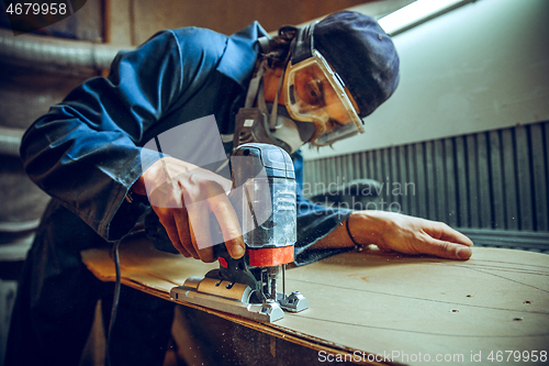 Image of Carpenter using circular saw for cutting wooden boards.