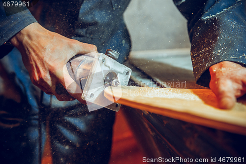 Image of Carpenter using circular saw for cutting wooden boards.