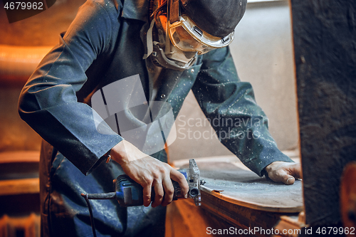 Image of Carpenter using circular saw for cutting wooden boards.