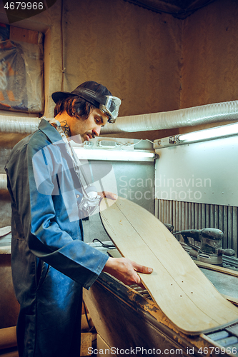 Image of Portrait of handsome carpenter working with skate at workshop