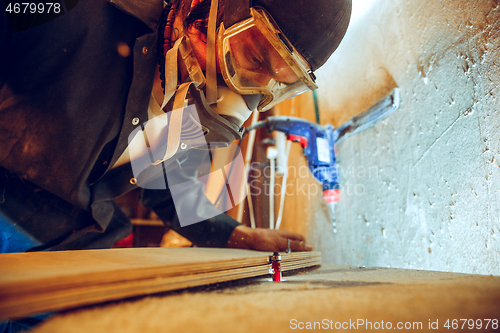 Image of Portrait of handsome carpenter working with skate at workshop