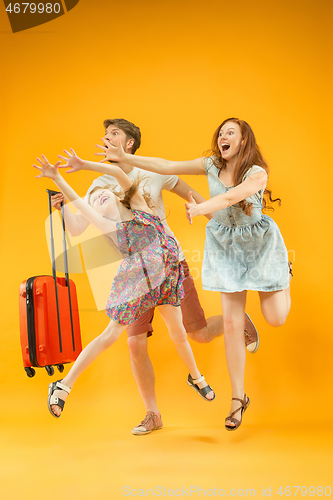 Image of Happy parents with daughter and suitcase at studio isolated on yellow background