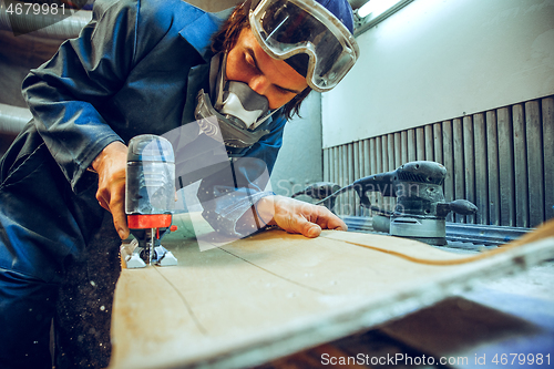 Image of Carpenter using circular saw for cutting wooden boards.