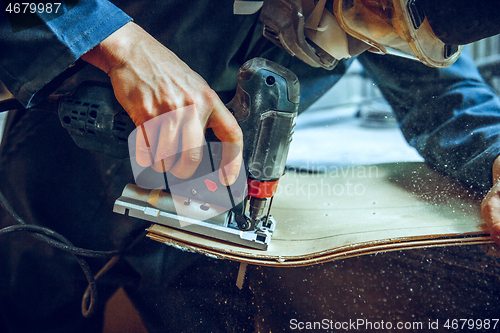 Image of Carpenter using circular saw for cutting wooden boards.