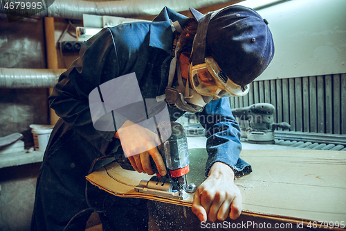 Image of Carpenter using circular saw for cutting wooden boards.