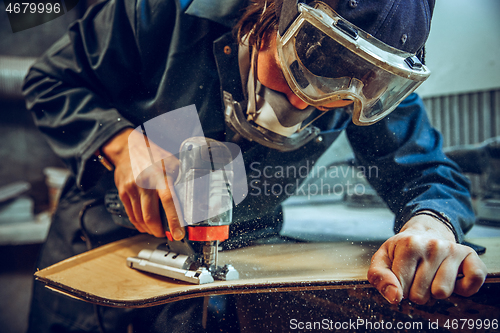 Image of Carpenter using circular saw for cutting wooden boards.