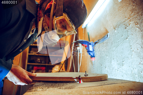 Image of Portrait of handsome carpenter working with skate at workshop