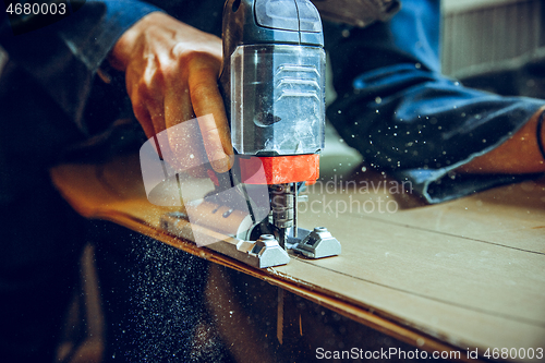 Image of Carpenter using circular saw for cutting wooden boards.