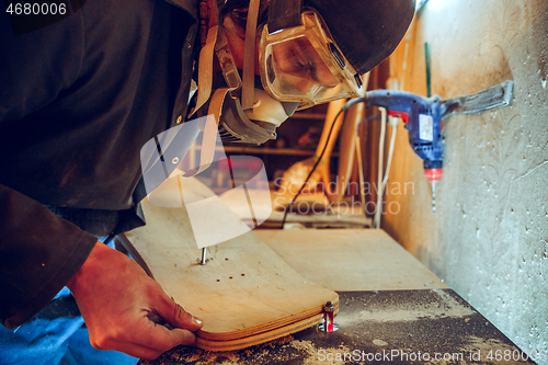 Image of Portrait of handsome carpenter working with skate at workshop