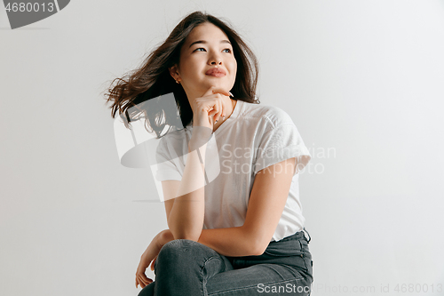 Image of Happy asian woman standing and smiling against gray background.