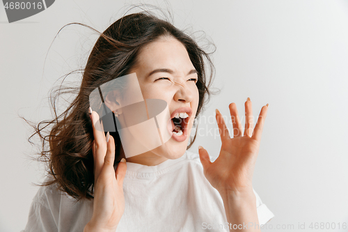 Image of The young emotional angry woman screaming on gray studio background