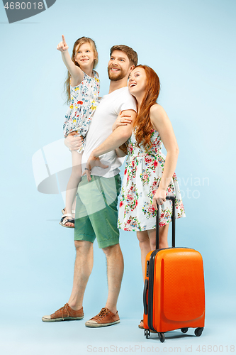 Image of Happy parent with daughter and suitcase at studio isolated on blue background