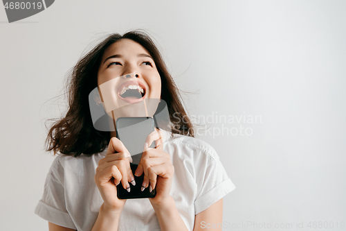 Image of Portrait of a confident casual asian girl showing blank screen of mobile phone