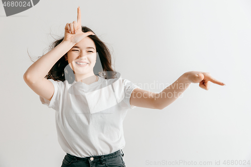 Image of Losers go home. Portrait of angry woman showing loser sign over forehead