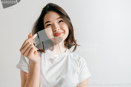 Image of Happy asian woman standing and smiling against gray background.