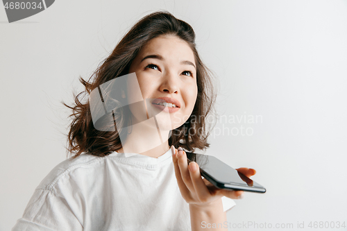 Image of Indoor portrait of attractive young asian woman holding blank smartphone