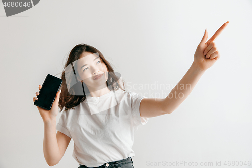 Image of Portrait of a confident casual asian girl showing blank screen of mobile phone