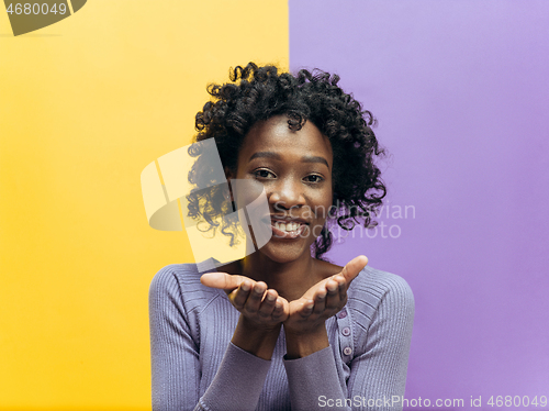 Image of The happy african woman standing and smiling against color background.