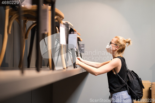 Image of New normal during covid epidemic. Caucasian woman shopping at retail furniture and home accessories store wearing protective medical face mask to prevent spreading of corona virus