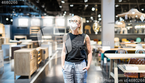 Image of New normal during covid epidemic. Caucasian woman shopping at retail furniture and home accessories store wearing protective medical face mask to prevent spreading of corona virus