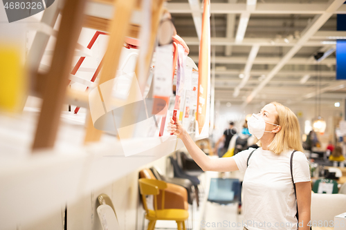 Image of New normal during covid epidemic. Caucasian woman shopping at retail furniture and home accessories store wearing protective medical face mask to prevent spreading of corona virus