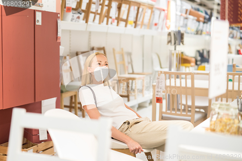 Image of New normal during covid epidemic. Caucasian woman shopping at retail furniture and home accessories store wearing protective medical face mask to prevent spreading of corona virus