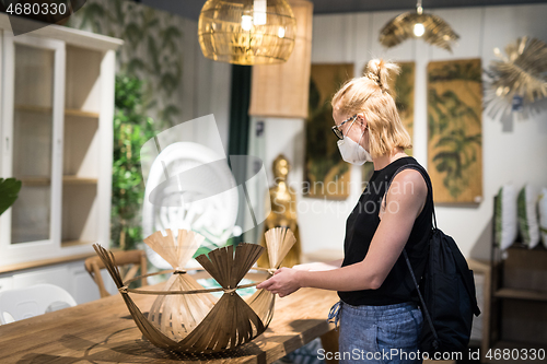 Image of New normal during covid epidemic. Caucasian woman shopping at retail furniture and home accessories store wearing protective medical face mask to prevent spreading of corona virus