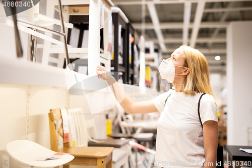 Image of New normal during covid epidemic. Caucasian woman shopping at retail furniture and home accessories store wearing protective medical face mask to prevent spreading of corona virus