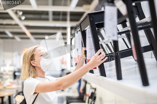 Image of New normal during covid epidemic. Caucasian woman shopping at retail furniture and home accessories store wearing protective medical face mask to prevent spreading of corona virus