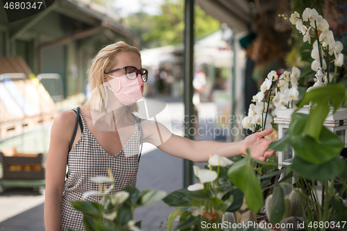 Image of Casual woman shopping outdoor at open market stalls wearing fase masks for protection from corona virus pandemic in Munchen, Germany