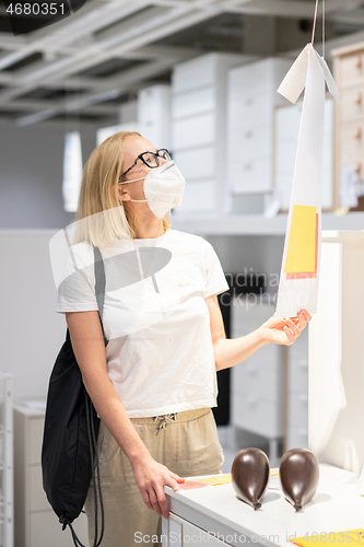 Image of New normal during covid epidemic. Caucasian woman shopping at retail furniture and home accessories store wearing protective medical face mask to prevent spreading of corona virus