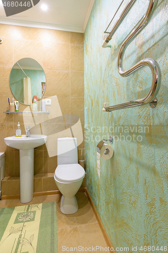 Image of Fragment of the bathroom interior, view of the toilet and washbasin, a heated towel rail is installed on the wall