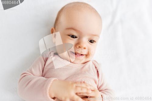 Image of sweet baby girl lying on white blanket