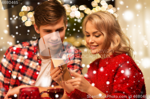 Image of couple with smartphone at home christmas dinner