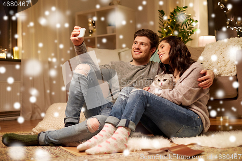 Image of happy couple taking selfie by smartphone at home