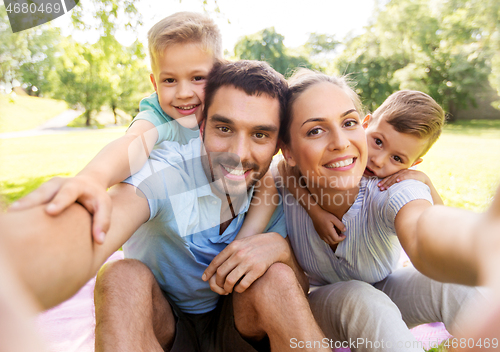 Image of family having picnic and taking selfie at park