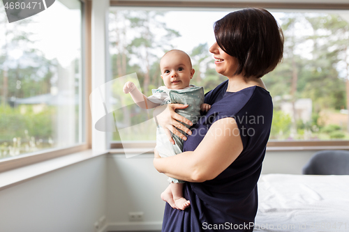 Image of middle-aged mother holding baby daughter at home
