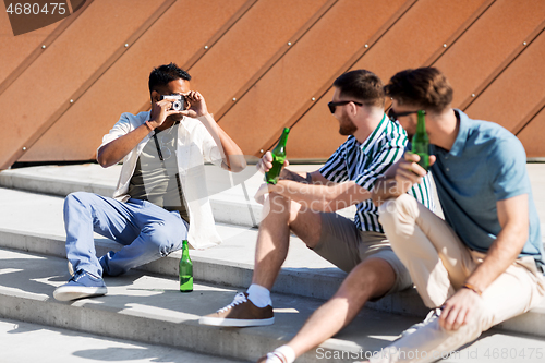 Image of man photographing friends drinking beer on street