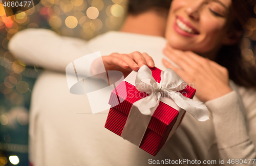 Image of close up of couple with christmas gift hugging