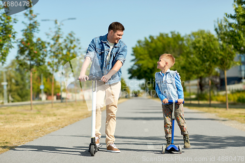 Image of father and little son riding scooters in city