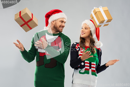 Image of happy couple in christmas sweaters with gifts