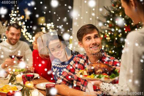 Image of happy friends having christmas dinner at home