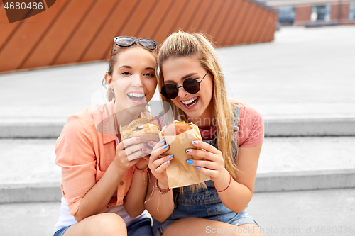 Image of teenage girls or friends eating burgers outdoors