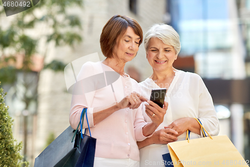 Image of old women with shopping bags and cellphone in city