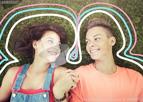 Image of happy teenage couple lying on grass at summer