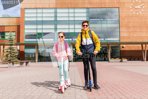 Image of school children with backpacks riding scooters