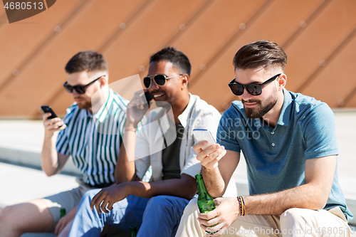 Image of men with smartphones drinking beer on street