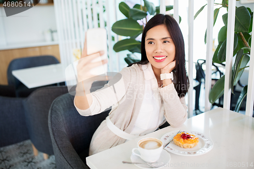 Image of asian woman taking selfie by smartphone at cafe