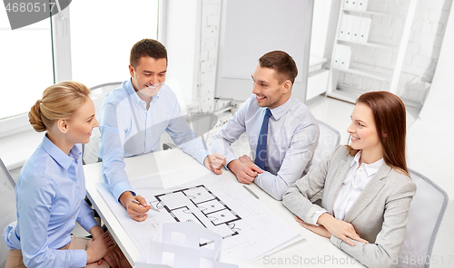 Image of happy business team discussing blueprint at office